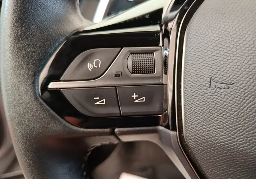 Gros plan sur les commandes de volume et téléphone du volant cuir du Peugeot 2008 gris clair, version 2022.