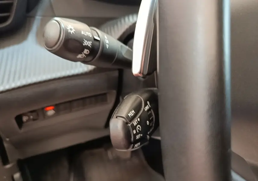 Gros plan sur le volant noir et les commandes de régulateur de vitesse du Peugeot 2008 gris clair, version Allure Pack 2022.