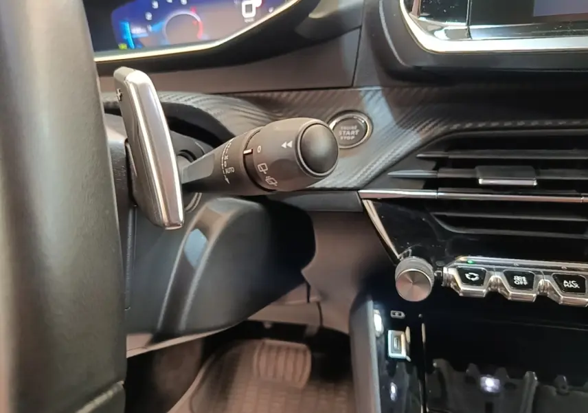 Gros plan intérieur côté conducteur du Peugeot 2008 2022, montrant la commande d’essuie-glace, bouton démarrage et partie du tableau de bord.