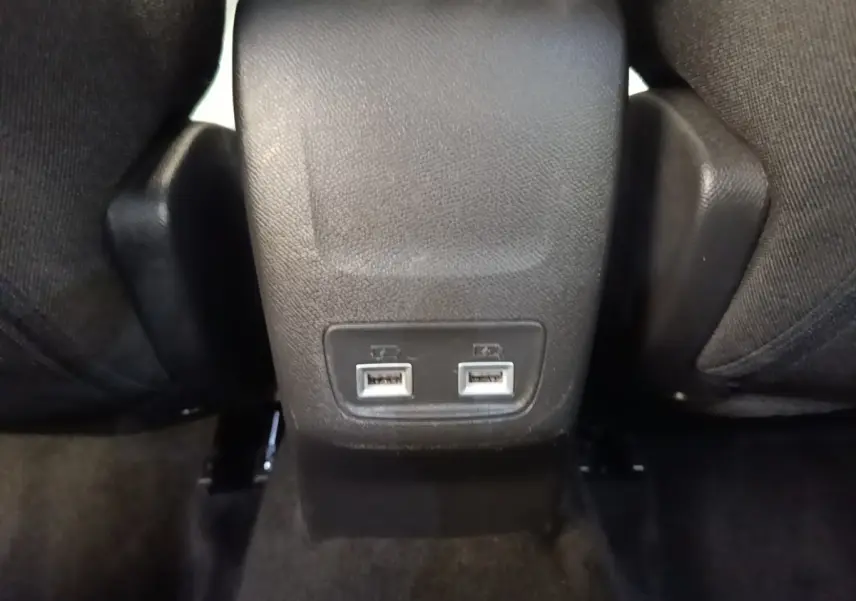 Gros plan sur la console centrale arrière noire du Peugeot 2008 gris clair, montrant deux ports USB pour les passagers arrière.
