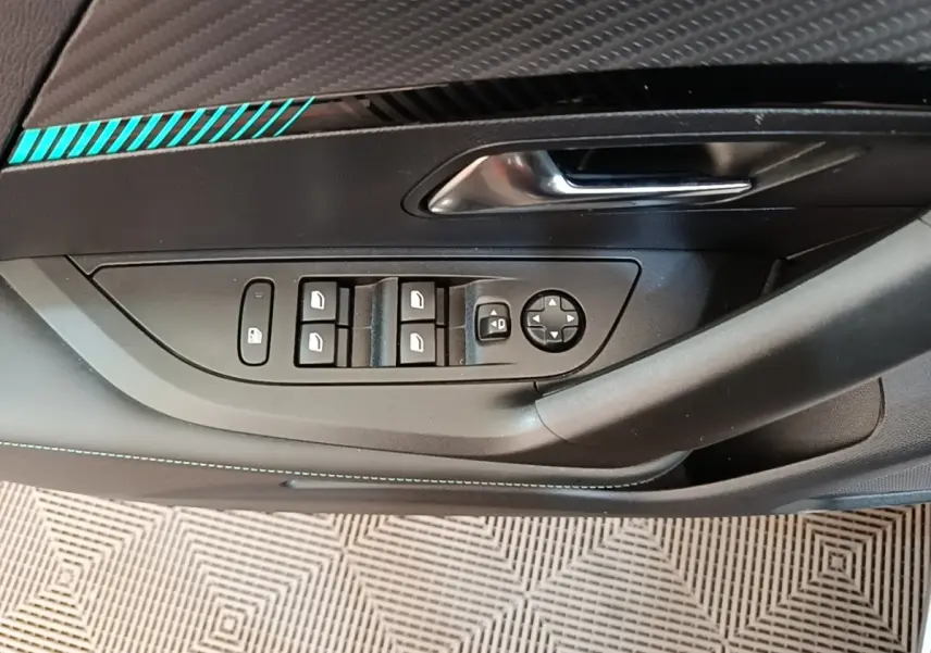 Gros plan sur la commande des vitres et rétroviseurs côté gauche du Peugeot 2008 gris clair avec surpiqûres bleues.