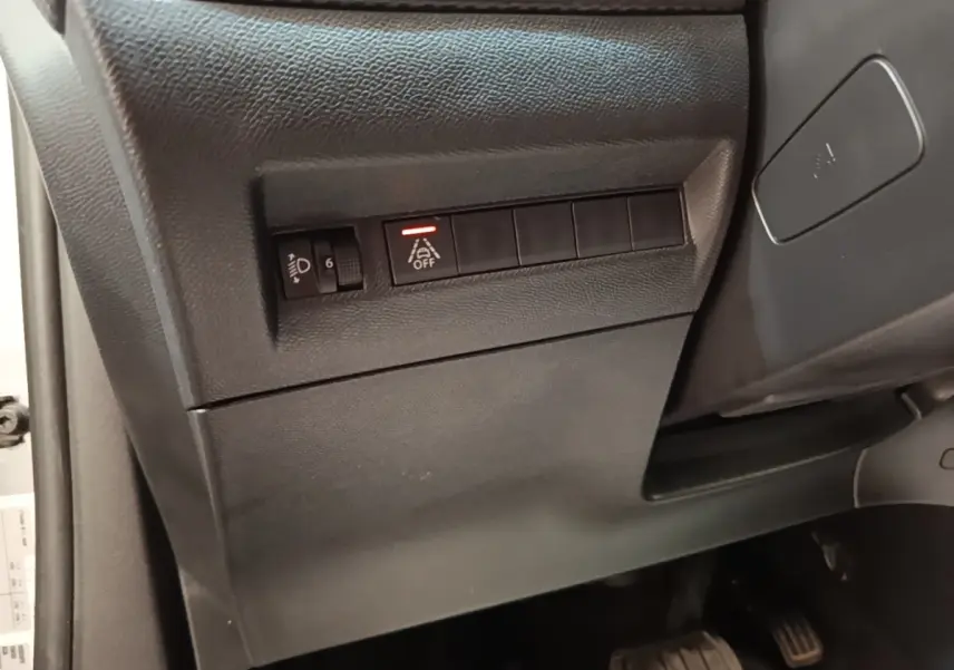 Détail intérieur côté gauche du tableau de bord noir avec commandes d'aide à la conduite sur Peugeot 2008 gris clair.