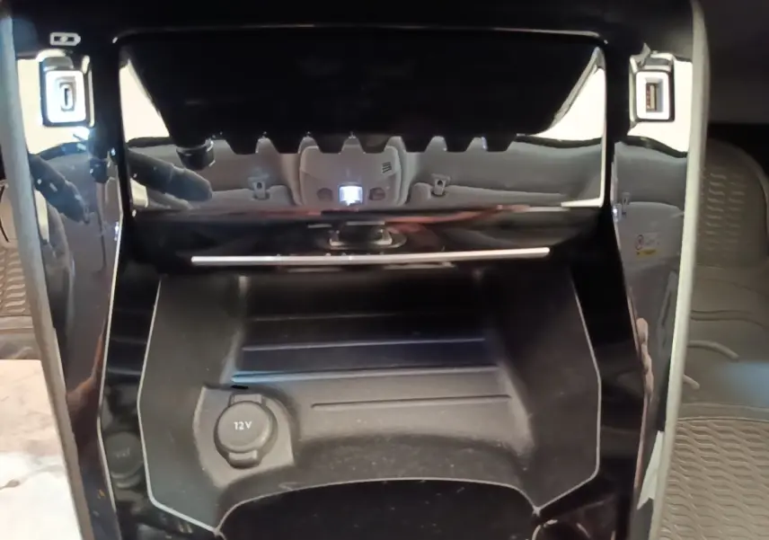 Gros plan sur la console centrale noire du Peugeot 2008 gris clair, avec prise 12V et ports USB visibles.