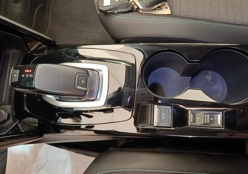 Vue plongeante sur la console centrale noire brillante du Peugeot 2008 gris clair avec levier de boîte auto et porte-gobelets.