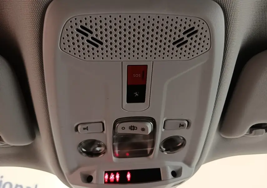 Vue intérieure du plafonnier avant du Peugeot 2008 gris clair, avec boutons d’éclairage et alerte SOS rouge.