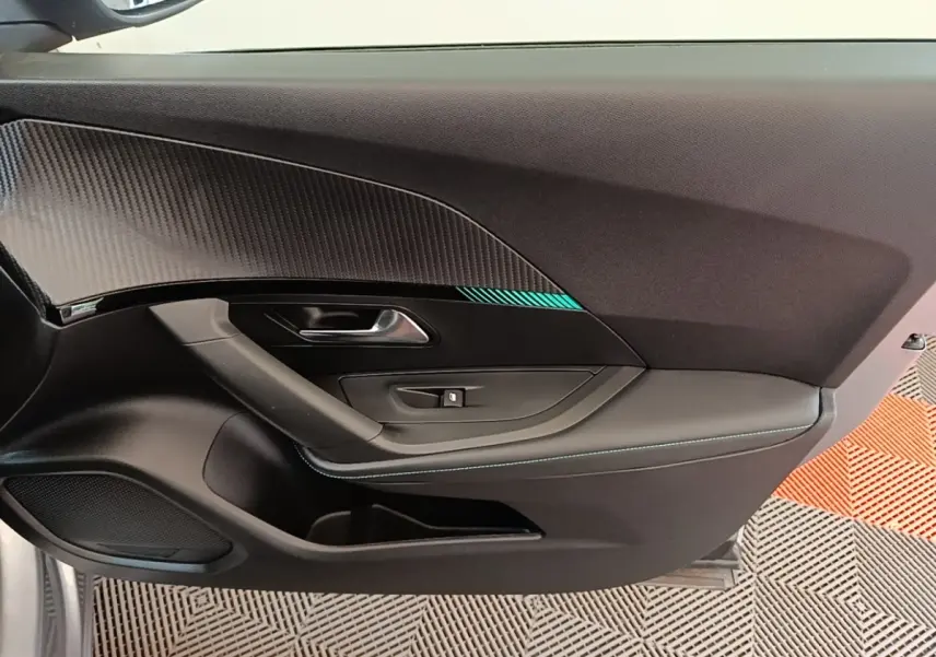 Vue rapprochée de la porte avant gauche du Peugeot 2008 gris clair avec insert décoratif et surpiqûres bleues.