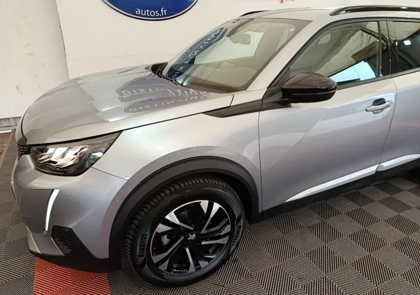 Vue 3/4 avant gauche d’un Peugeot 2008 gris clair avec jantes noires et rétroviseur noir brillant.