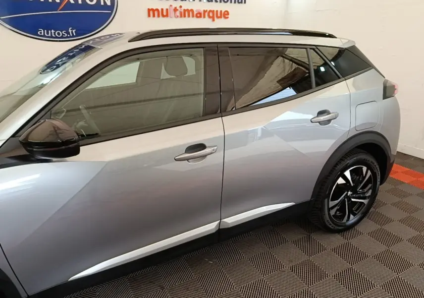 Vue côté gauche du Peugeot 2008 gris clair 2022 avec rétroviseurs noirs et jantes alliage noires.