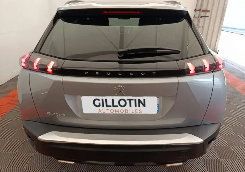 Vue arrière du Peugeot 2008 gris clair 2022 avec feux LED allumés et logo Peugeot visible sur le hayon.