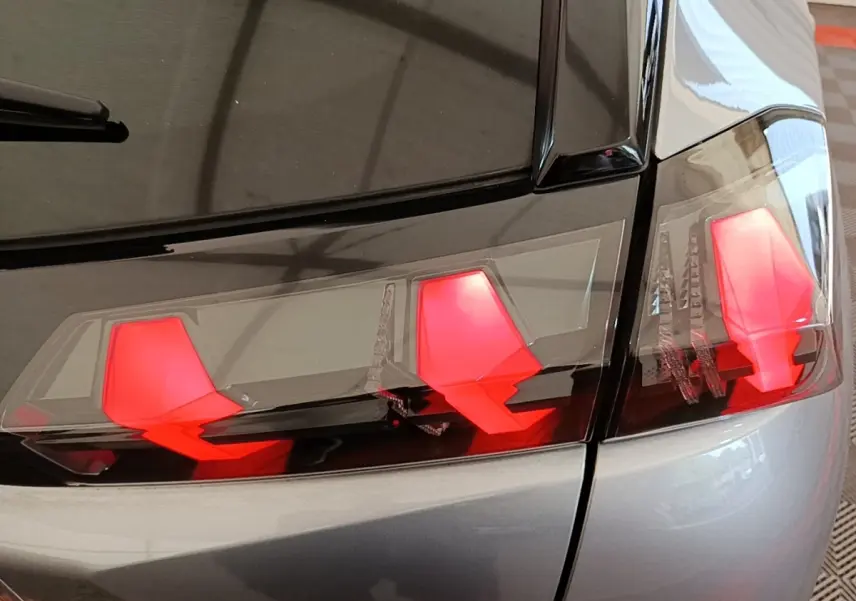 Gros plan sur les feux arrière rouges du côté gauche d’un Peugeot 2008 gris clair, finition Allure Pack 2022.