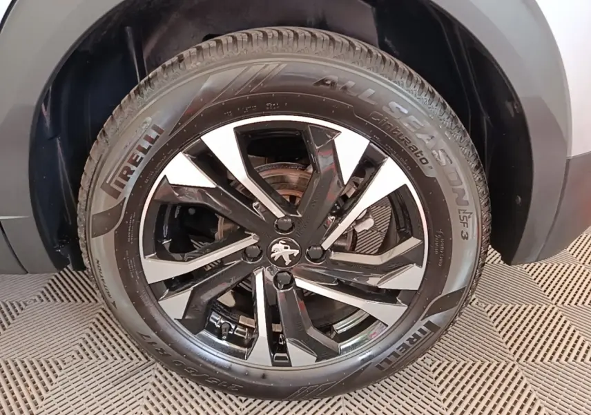 Gros plan sur la roue avant droite d’un Peugeot 2008 gris clair avec jante alliage noire et argentée, pneu Pirelli.