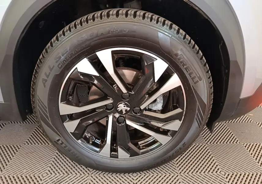 Gros plan sur la roue avant gauche gris clair du Peugeot 2008 avec jante alliage noire et argentée au design moderne.