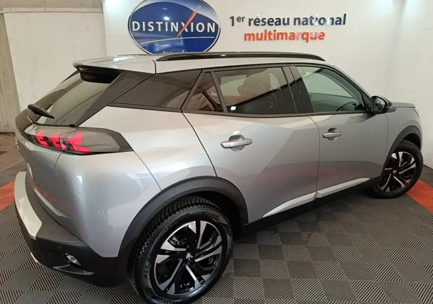 Vue 3/4 arrière droite d'un Peugeot 2008 gris clair 2022 avec jantes noires et feux arrière LED distinctifs.