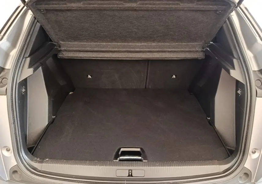 Coffre ouvert vu de l'arrière d'un Peugeot 2008 gris clair, montrant un espace de chargement propre et spacieux.
