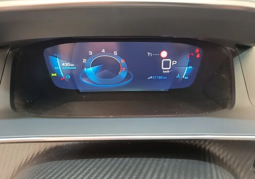Gros plan sur le tableau de bord numérique du Peugeot 2008 gris clair, affichant la vitesse, autonomie et température moteur.