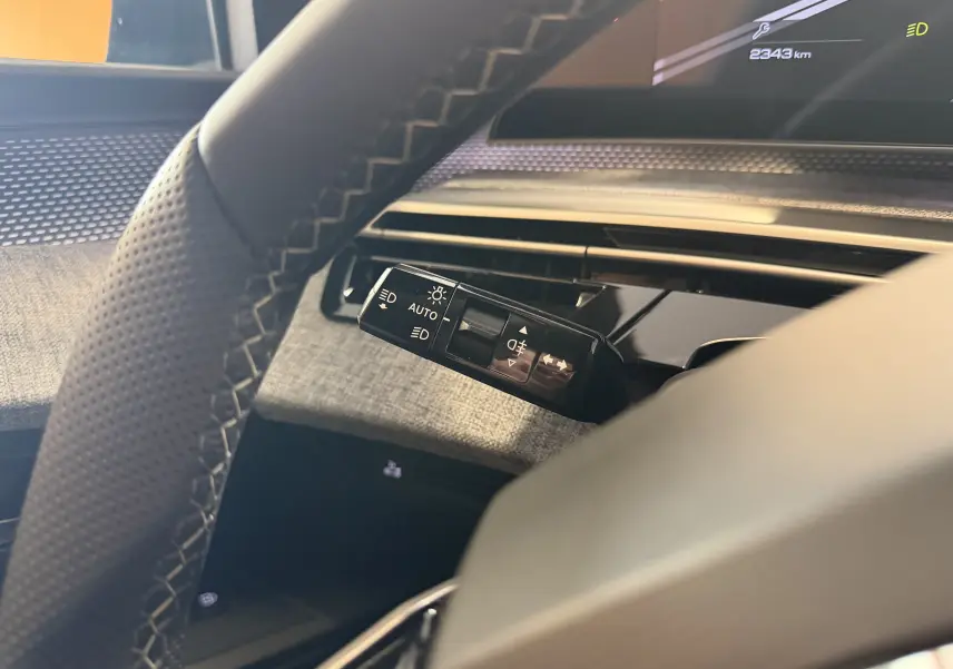 Gros plan sur la commande des feux et clignotants côté gauche du volant dans l’habitacle du Peugeot 3008 Hybrid 2025.