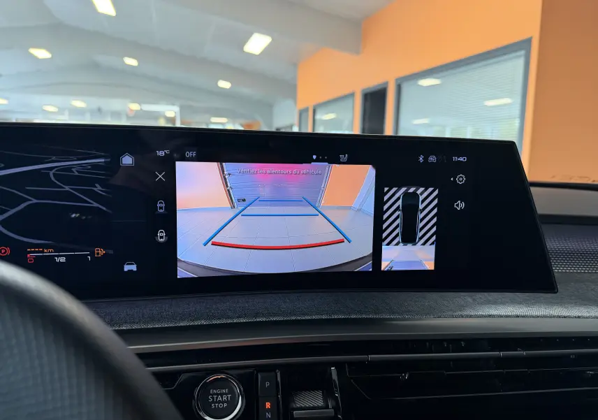 Vue intérieure du tableau de bord du Peugeot 3008 Hybrid 145 GT avec écran affichant la caméra de recul et l’aide au stationnement.