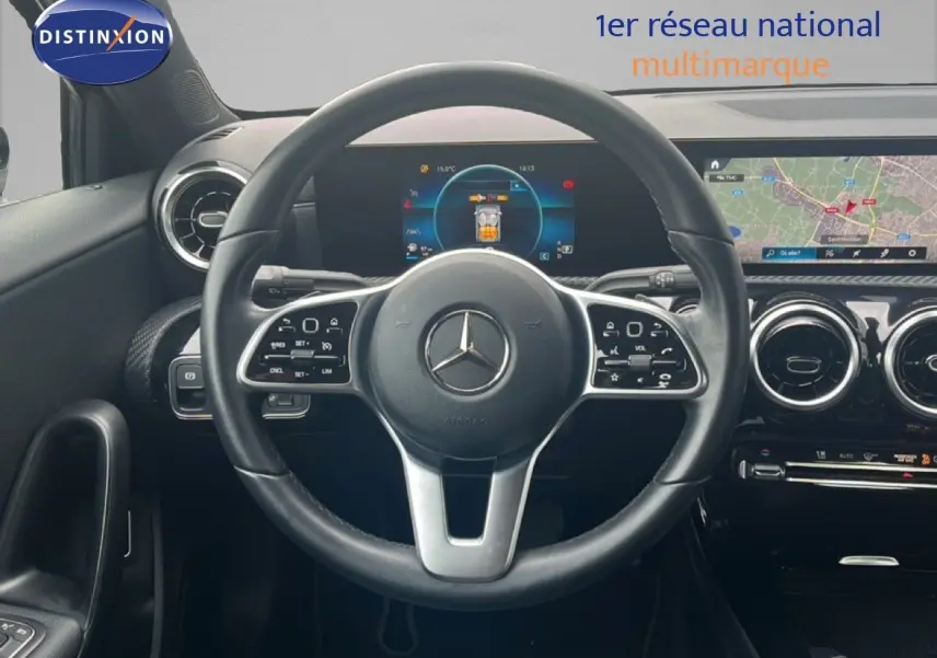 Vue intérieure centrée sur le volant cuir noir d'une Mercedes Classe A 180 Business Line avec écran digital et navigation.