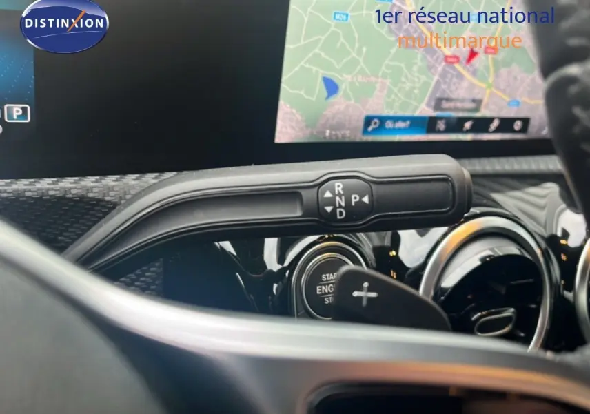 Gros plan sur la commande de boîte automatique et l'écran de navigation du tableau de bord d'une Mercedes Classe A noire.