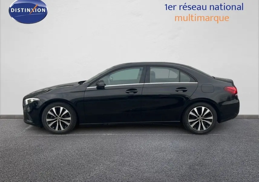 Vue de profil côté gauche d'une Mercedes Classe A 180 Business Line noire Cosmos métal avec jantes alliage bicolores.