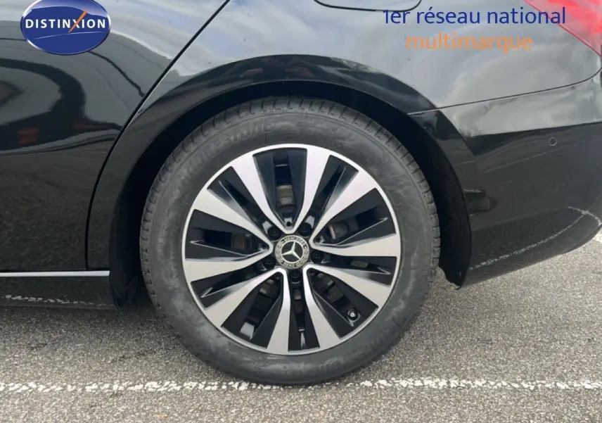 Gros plan sur la roue arrière droite d'une Mercedes Classe A 180 Business Line noire Cosmos Metal avec jante alliage bicolore.