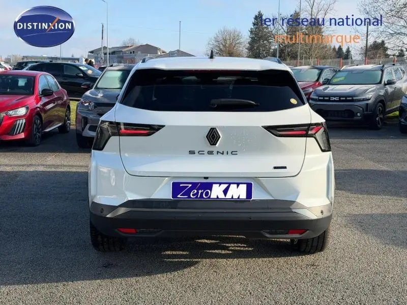 Vue arrière d’un Renault Scénic blanc électrique 2025 avec feux LED et logo distinctif sur parking.
