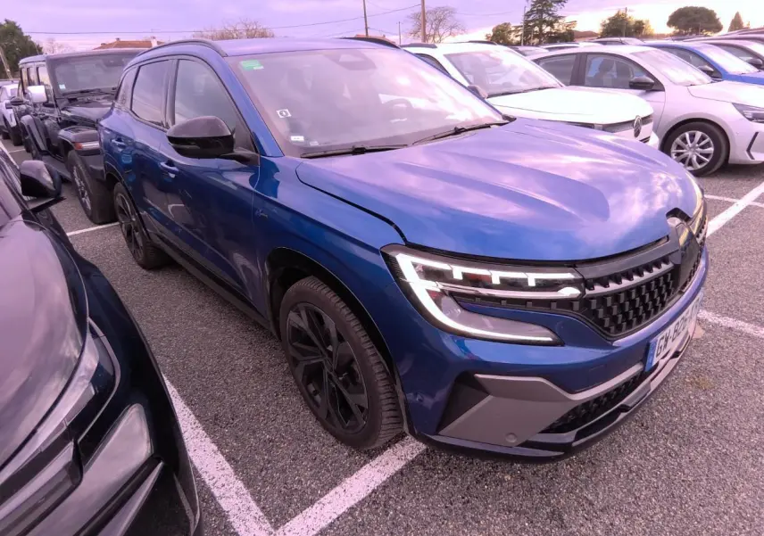 Renault Austral bleu Iron en 3/4 avant droit, avec calandre damier ice black et jantes alliage noires.