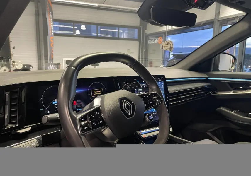 Vue intérieure côté conducteur du Renault Austral 2024, volant Alcantara et tableau de bord numérique avec éclairage bleu.