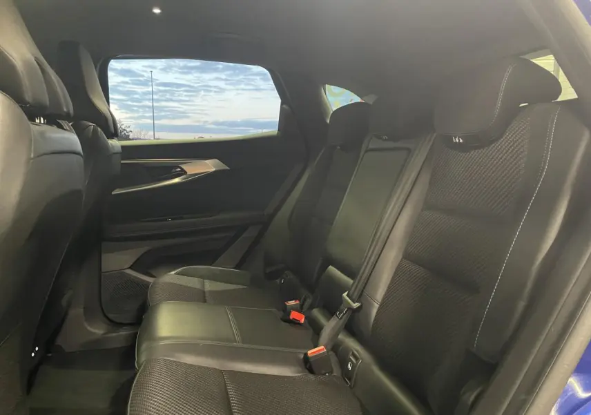 Vue intérieure arrière côté droit du Renault Austral 2024, sièges en tissu et Alcantara noirs avec surpiqûres bleues.