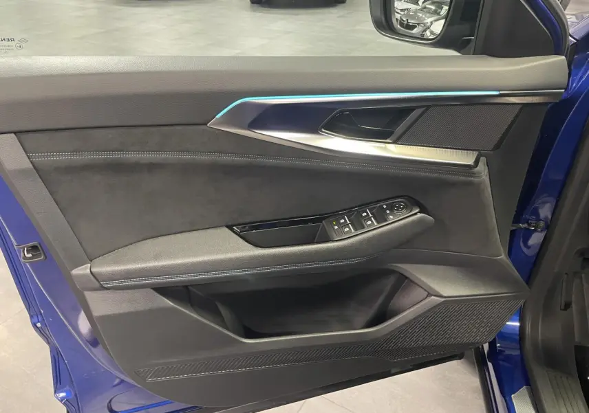 Vue côté gauche de la porte avant ouverte d’un Renault Austral 2024 bleu avec garniture Alcantara et commandes électriques.