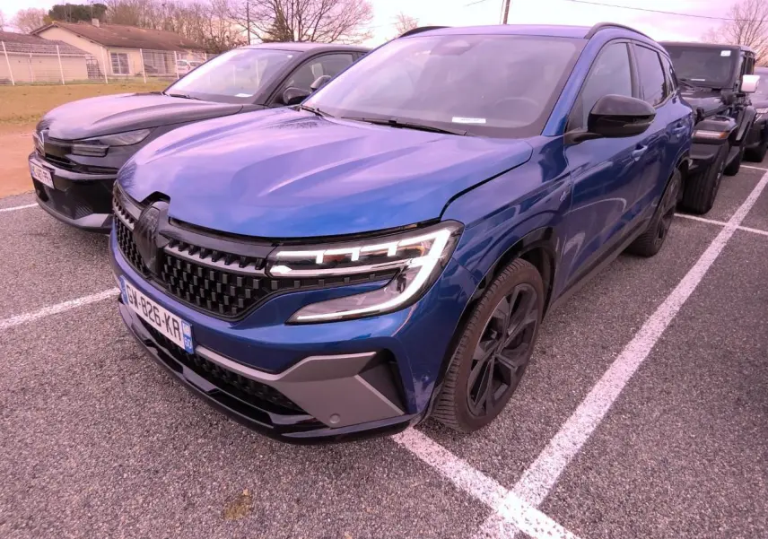 Vue 3/4 avant droite d'un Renault Austral 2024 bleu Iron avec calandre à damier et jantes alliage noires.