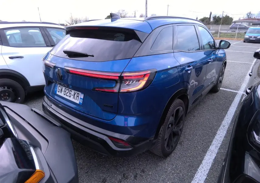 Vue 3/4 arrière droite d'un Renault Austral 2024 bleu Iron avec feux LED et jantes alliage noires.