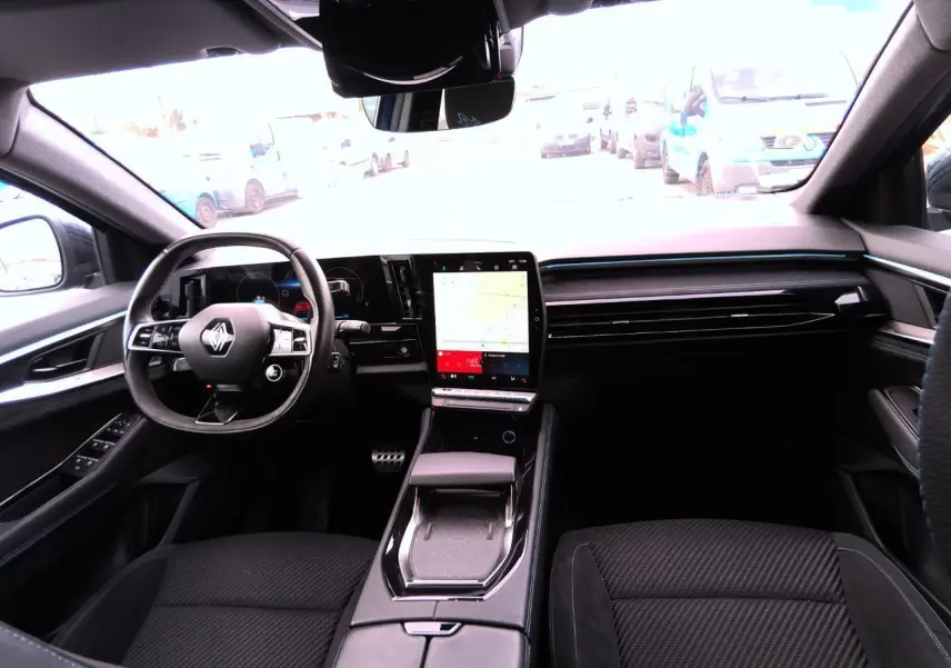 Vue intérieure avant du Renault Austral 2024, tableau de bord noir avec écran tactile vertical et volant Alcantara.
