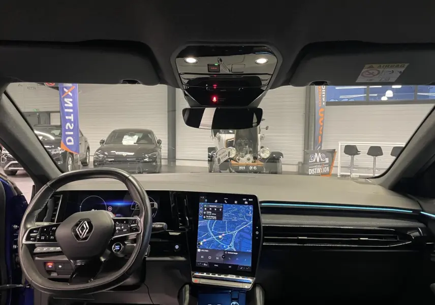 Vue intérieure avant du Renault Austral 2024 bleu, tableau de bord avec écran tactile vertical et volant multifonction.