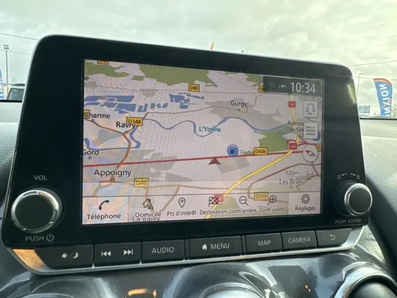 Écran tactile central du Nissan Juke 2022 affichant la navigation GPS avec commandes audio et volume visibles.