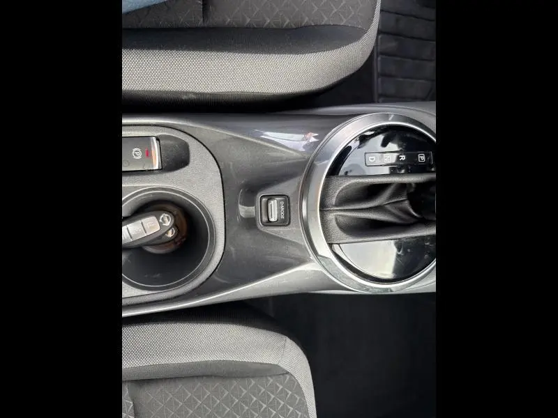 Vue plongeante sur la console centrale noire du Nissan Juke 2022 avec levier de vitesse automatique et clé insérée.