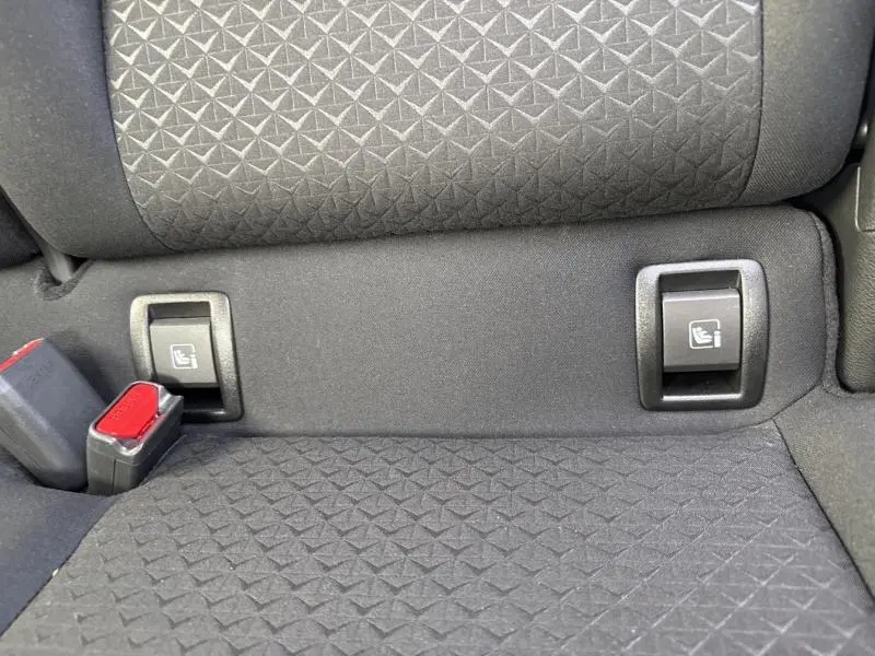 Détail des fixations Isofix et ceintures de sécurité sur la banquette arrière tissu noir du Nissan Juke gris perle métallisé.
