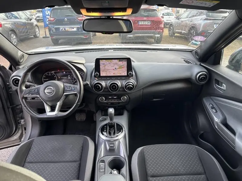Vue intérieure avant du Nissan Juke 2022 avec tableau de bord noir, écran tactile central et volant cuir multifonction.