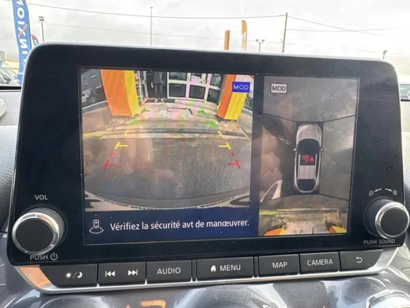 Écran tactile intérieur montrant la caméra de recul et la vue 360° du Nissan Juke gris perle métallisé, tableau de bord visible.