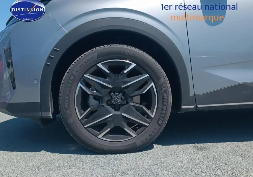 Gros plan sur la roue avant gauche du Peugeot 5008 gris artense, mettant en valeur la jante alu au design moderne.