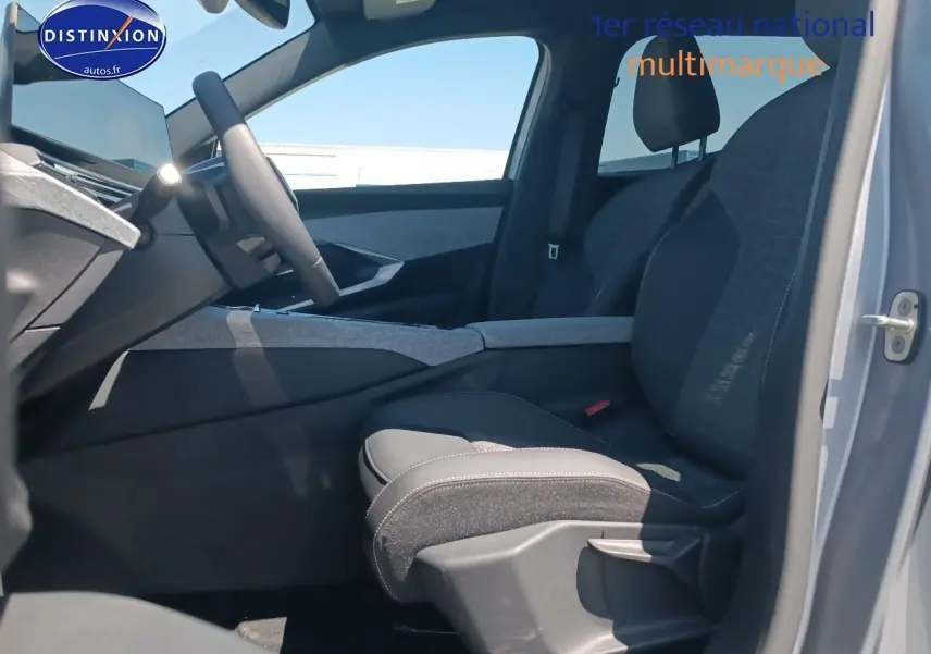Vue intérieure côté conducteur du Peugeot 5008 gris Artense, mettant en valeur les sièges en tissu et l'accoudoir central.