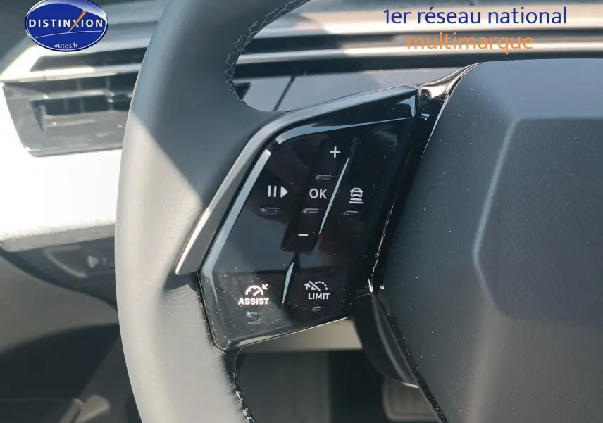 Gros plan sur le volant cuir multifonction à gauche du Peugeot 5008 gris Artense, avec commandes d'assistance visibles.