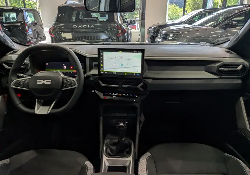Vue intérieure frontale du tableau de bord noir et gris du Dacia Bigster 2026 avec écran tactile central et volant multifonction.