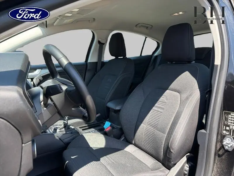 Vue intérieure côté conducteur de la Ford Focus 1.0 Flexifuel 125ch Business avec sièges tissu noir et volant cuir.