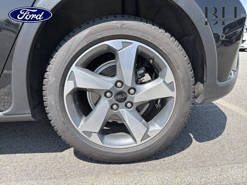 Gros plan sur la jante alliage grise et le pneu du côté avant droit d'une Ford Focus noir Agate métallisé.