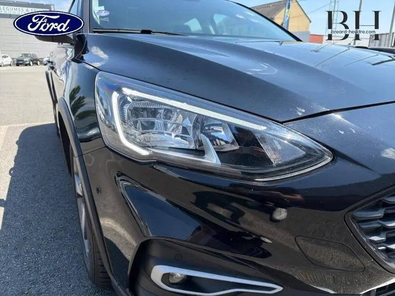 Gros plan sur l'avant droit d'une Ford Focus noir Agate métallisé, mettant en valeur le phare et la calandre.