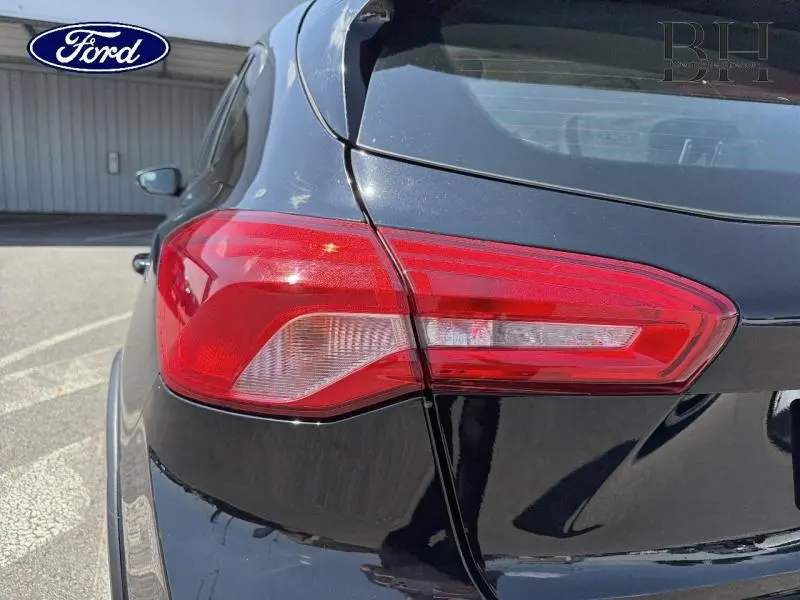 Gros plan sur le feu arrière droit d'une Ford Focus noir Agate métallisé, avec reflet sur la carrosserie brillante.