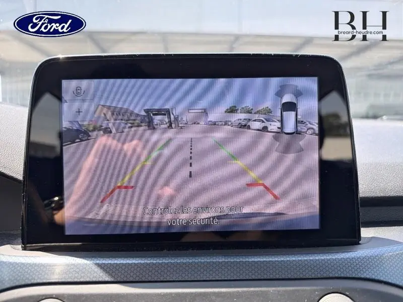 Écran tactile intérieur montrant la caméra de recul active d'une Ford Focus noire, vue depuis le tableau de bord.