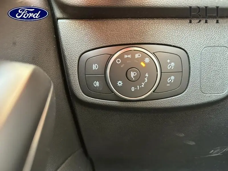 Gros plan sur le bouton de réglage des phares dans l'habitacle noir de la Ford Focus 2021.