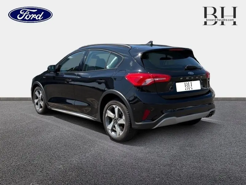 Vue 3/4 arrière droite d'une Ford Focus noire Agate métallisé avec jantes alu et barres de toit visibles.